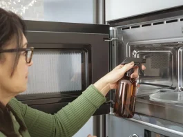 nő ecettel takarítja a mikrót