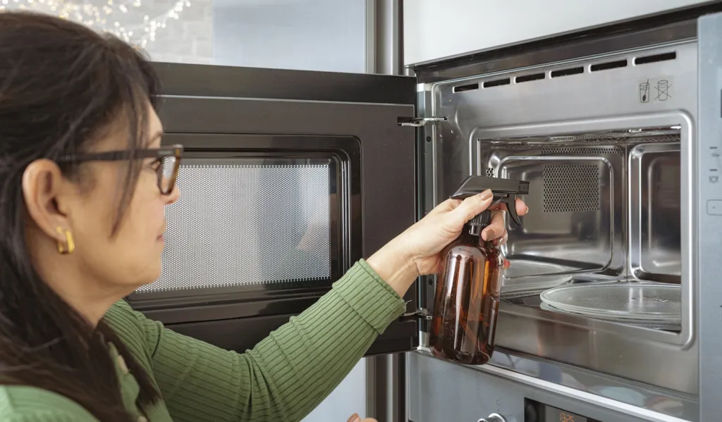 nő ecettel takarítja a mikrót