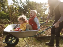 anyuka két kisgyerekével játszik ősszel a kertben