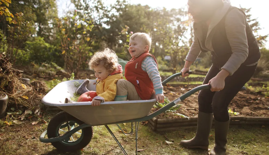 anyuka két kisgyerekével játszik ősszel a kertben