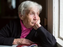 Egy idős nő néz ki az ablakon