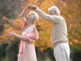 boldog idős pár táncol az őszi erdőben mert fitt az immunrendszerük