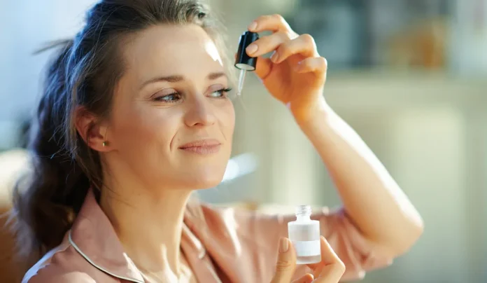 középkorú nő pizsamában retilnollal ápolja az arcát