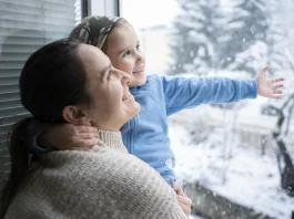 szellőzetés télen anya és kislánya állnak mosolyogva a nyitott ablaknál