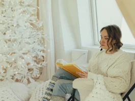 Függönyök mosása karácsony előtt: Stresszmentes tippek hófehér függönyök előtt ül a karácsonyfánál nő karácsonykor