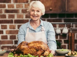 szép idős hölgy a konyhában egy egész grillcsirkével