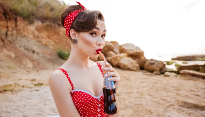 pinup girlnek öltözött lány ligh kólát iszik a tengerparton