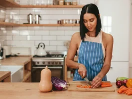 fa vágódeszkén zöldséget aprít egy fiatal háziasszony