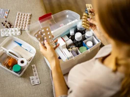 női kéz szépen elhelyezi a gyógyszert a háztartási elsősegélynyújtó készletben.